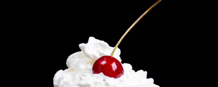 Cherry with whipped cream on a black background