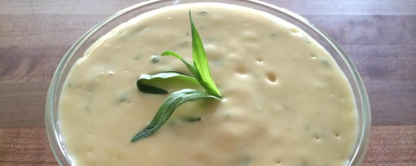 A bowl of Béarnaise sauce with a sprig of fresh Tarragon sticking out of it.