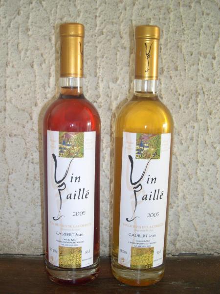 Photographie de deux bouteilles de vin paillé l'une contenant du vin rouge l'autre du vin blanc.