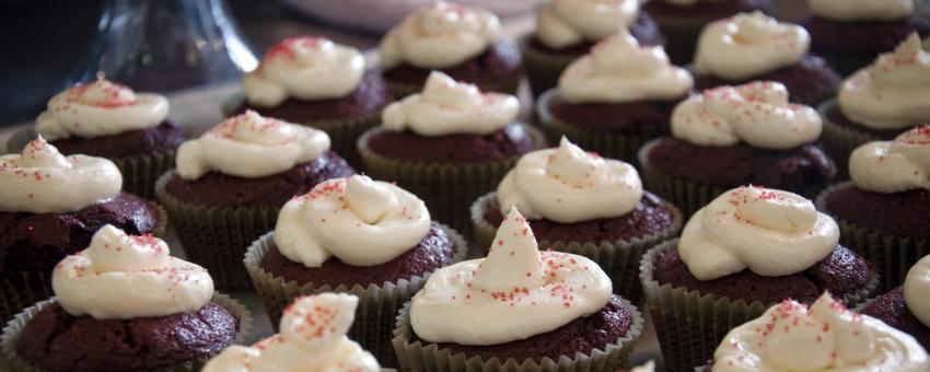 Chocolate cupcakes with cream icing and red sprinkles.