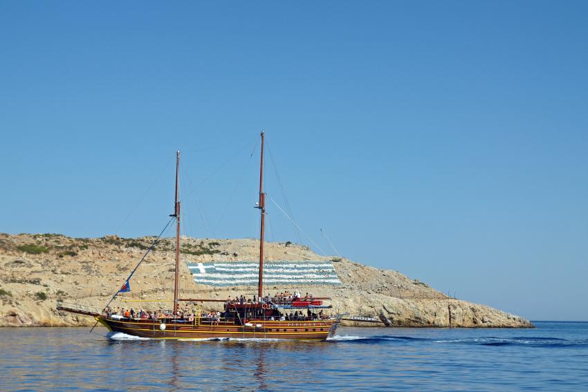 Tour boat cruising near the coast of Pserimos island, Greece.